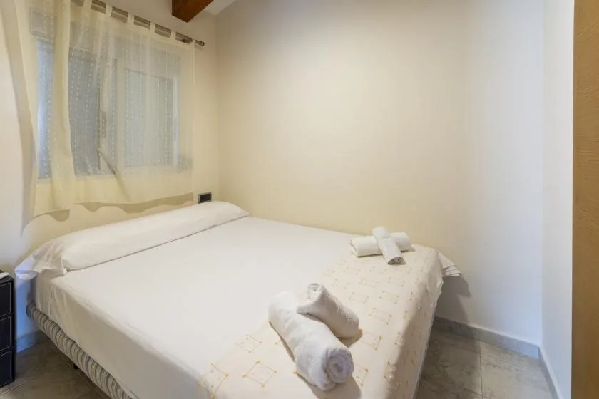 Dormitorio con una cama bien tendida y toallas dobladas.