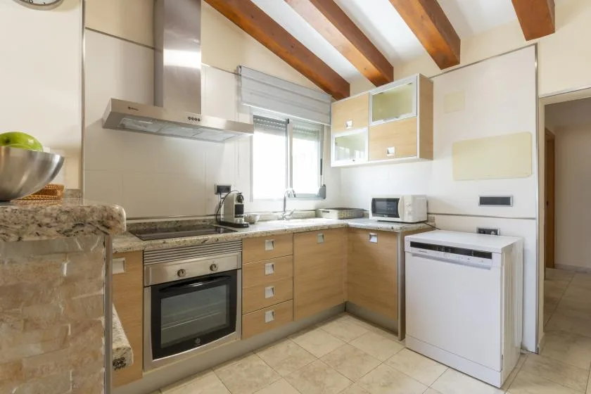 Una cocina luminosa con gabinetes de madera clara y un horno integrado.