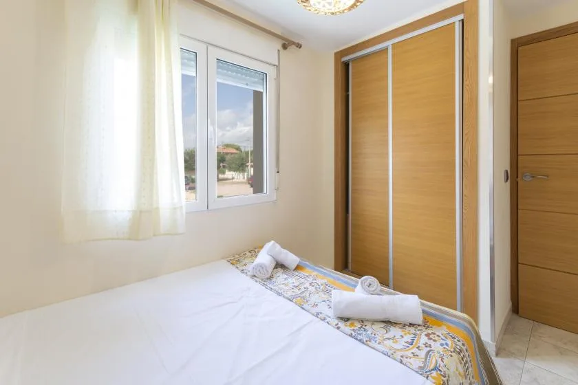 Un dormitorio luminoso con cama, ventana y armario de madera.