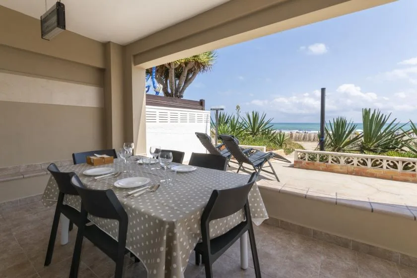 Un comedor exterior cubierto da a un patio con vistas al mar.