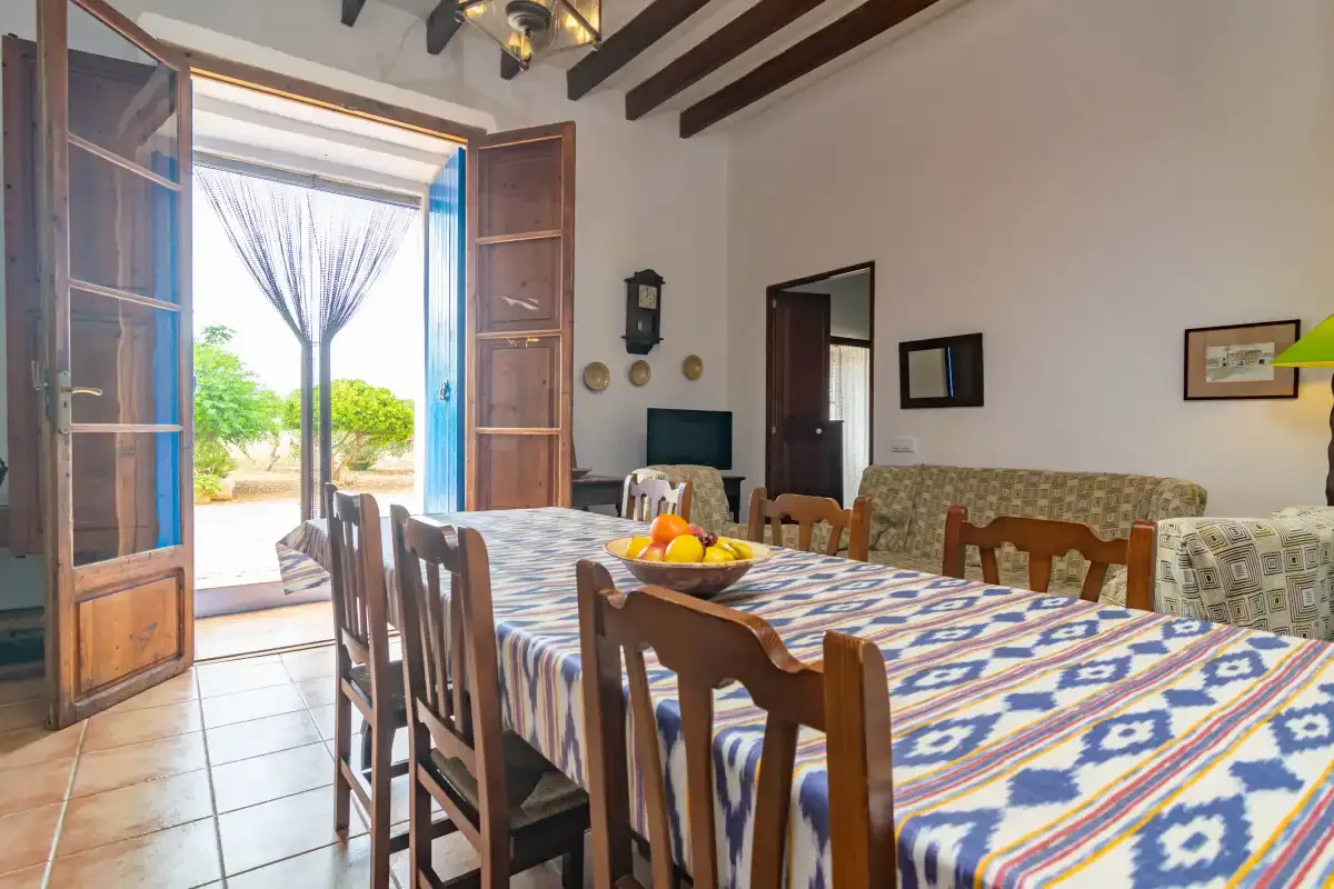 Un comedor con una mesa larga cubierta con un mantel estampado y sillas.