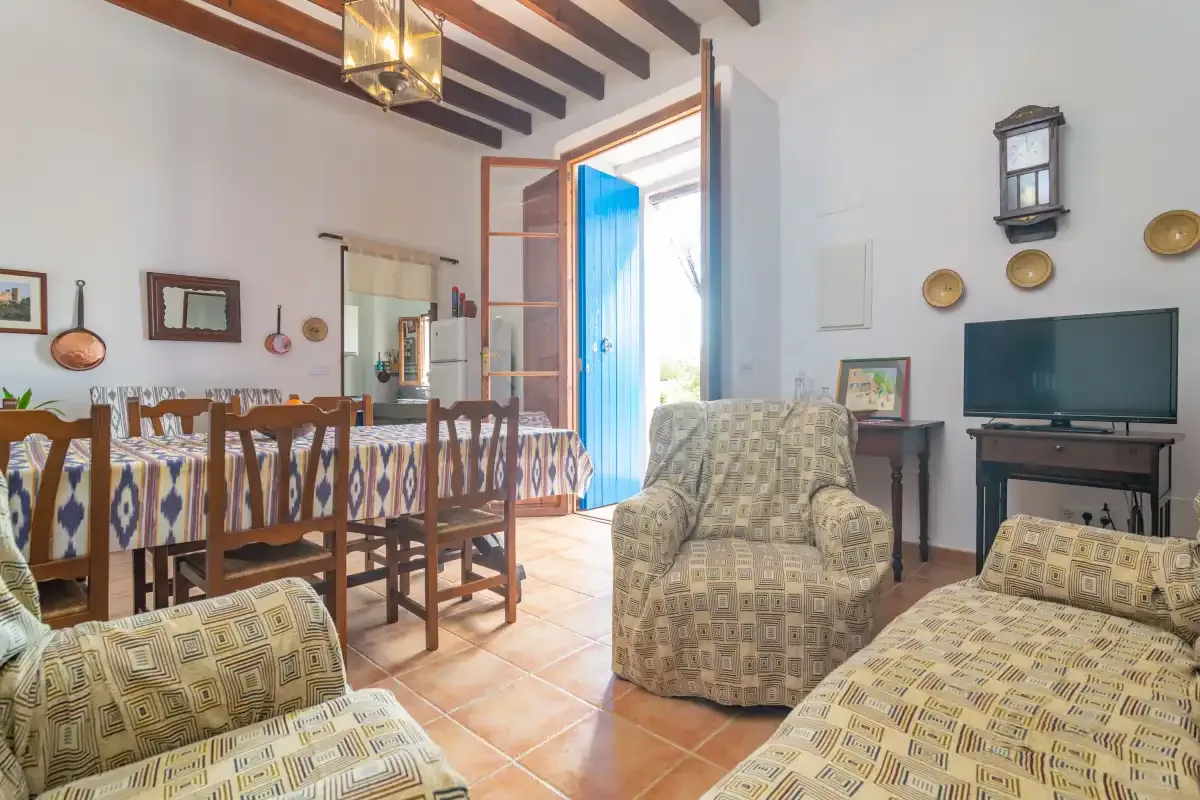 Una sala de estar y comedor con asientos estampados, una mesa de comedor y un televisor.