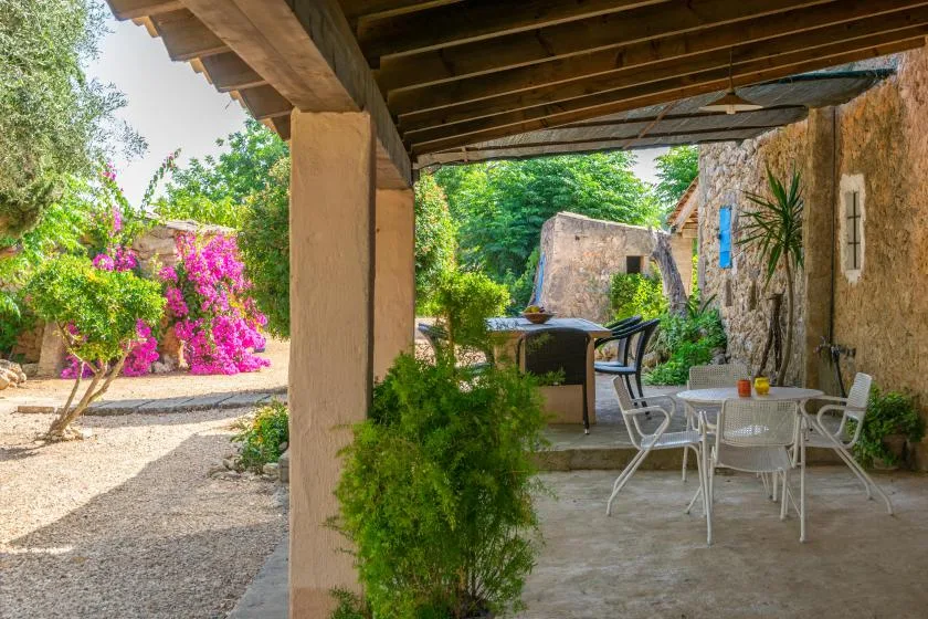 Un patio exterior cubierto con una mesa de comedor y asientos de jardín.