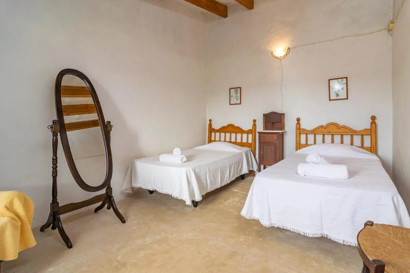 Un dormitorio con dos camas individuales, ropa de cama blanca y un espejo de pie.