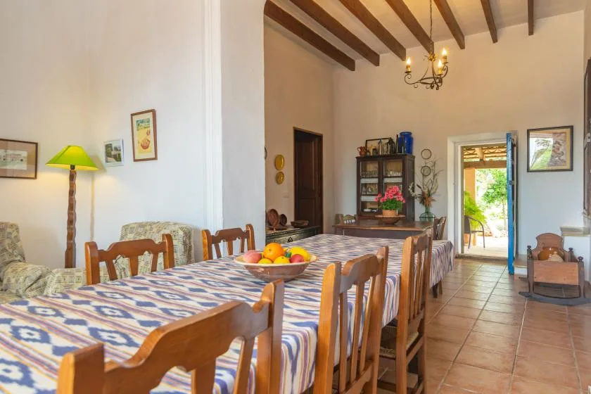 Un comedor con una mesa larga bajo vigas de techo expuestas.