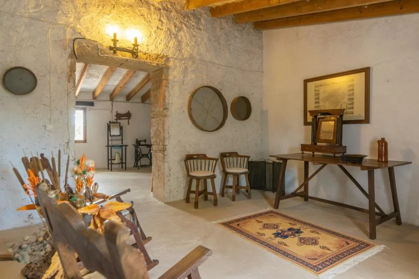 Una estancia rústica con asientos de madera, una mesa y una alfombra estampada.