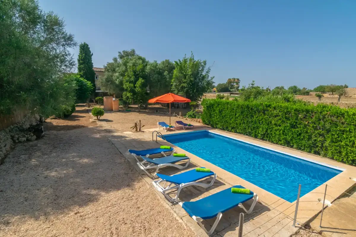 Una piscina al aire libre con tumbonas azules y una sombrilla naranja.