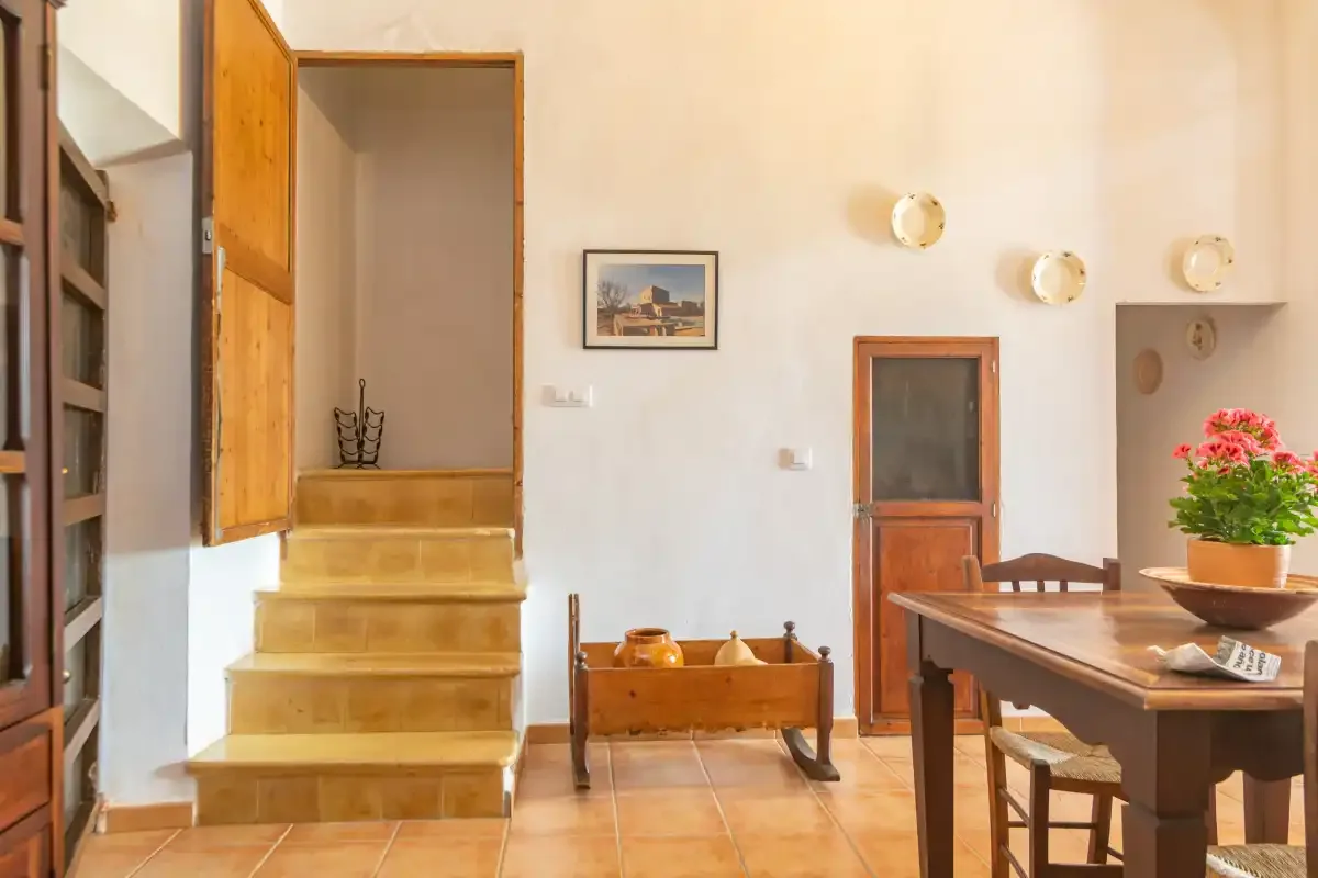 Un comedor con una mesa de madera junto a una escalera corta.