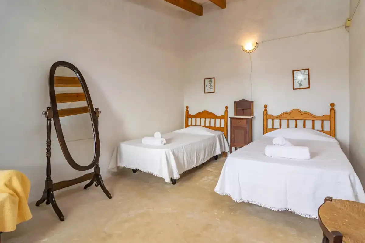 Un dormitorio con dos camas individuales, ropa de cama blanca y un espejo de pie.