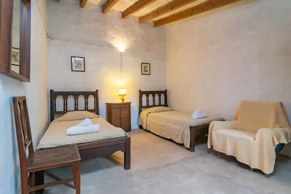 Un dormitorio con dos camas, una mesita de noche y asientos cubiertos.