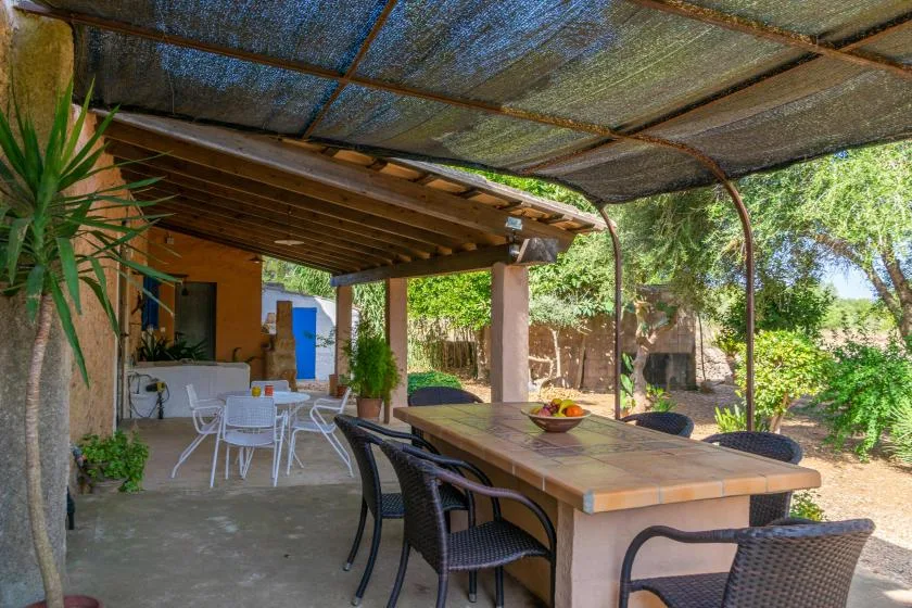 Una zona de comedor exterior cubierta con una mesa larga y asientos alrededor.