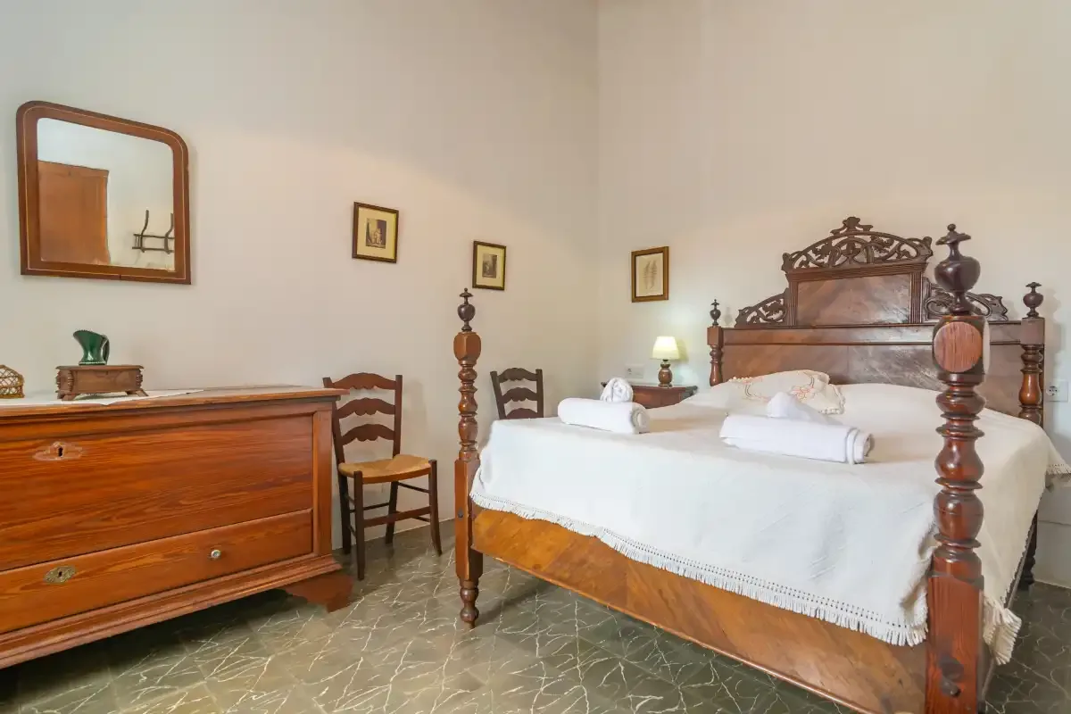 Un dormitorio con una cama de madera, ropa de cama blanca y una cómoda.