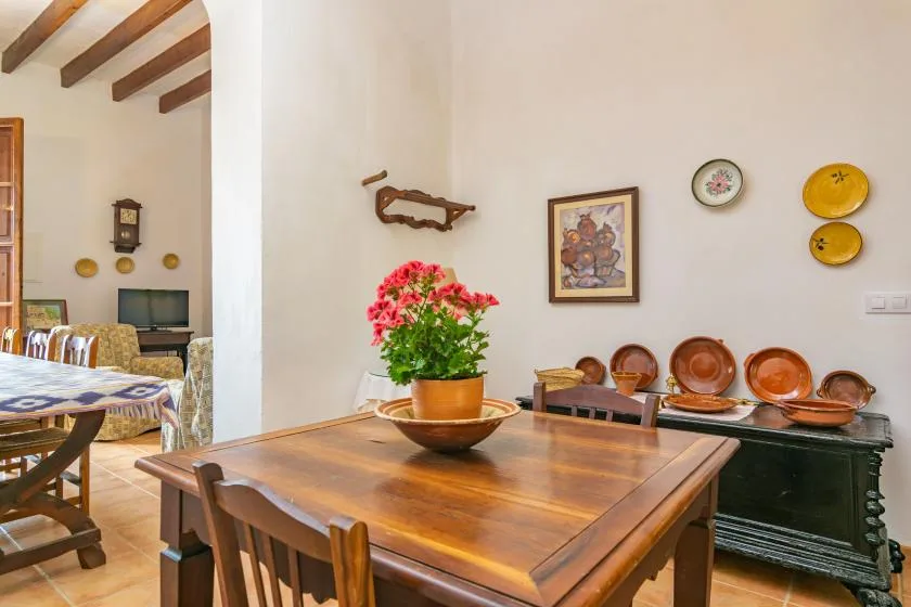 Un comedor con una mesa de madera y una planta con flores en una maceta.