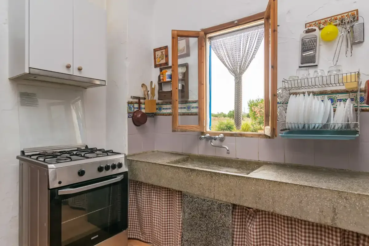 Una cocina compacta con estufa de gas, encimera y ventana abierta.