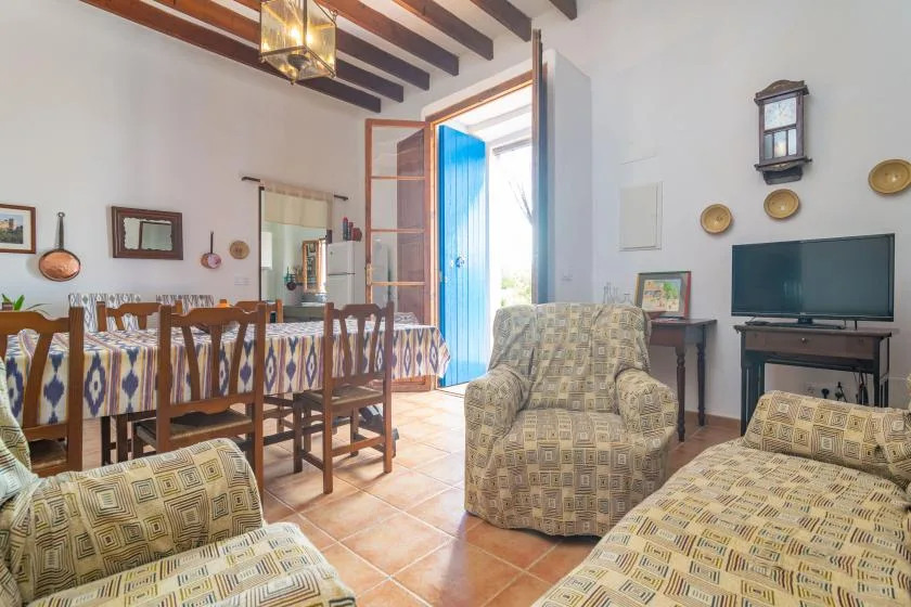 Una sala de estar y comedor con asientos estampados, una mesa y un televisor.