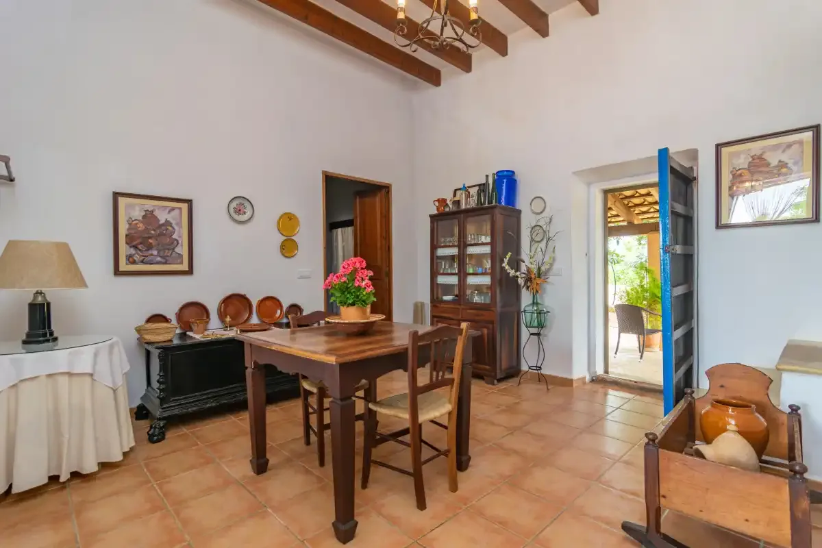 Un comedor con una mesa y sillas de madera, junto a una puerta abierta al exterior.