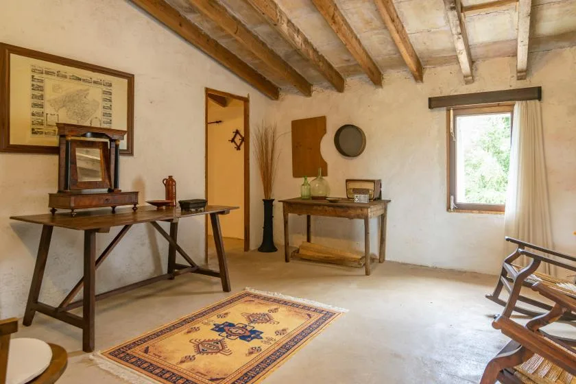 Una estancia rústica con vigas expuestas, mesas de madera y una alfombra estampada.