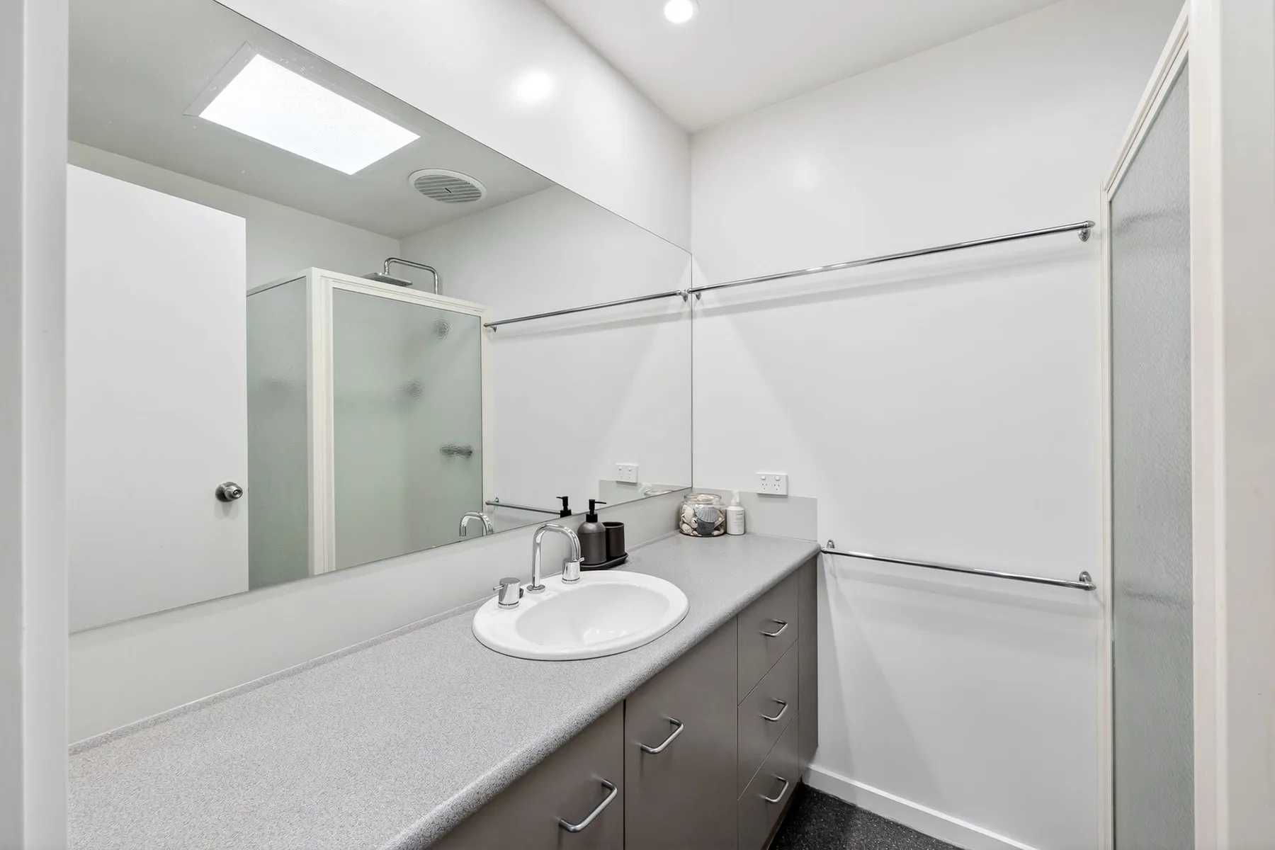 A bright bathroom with a sink, vanity, and shower.