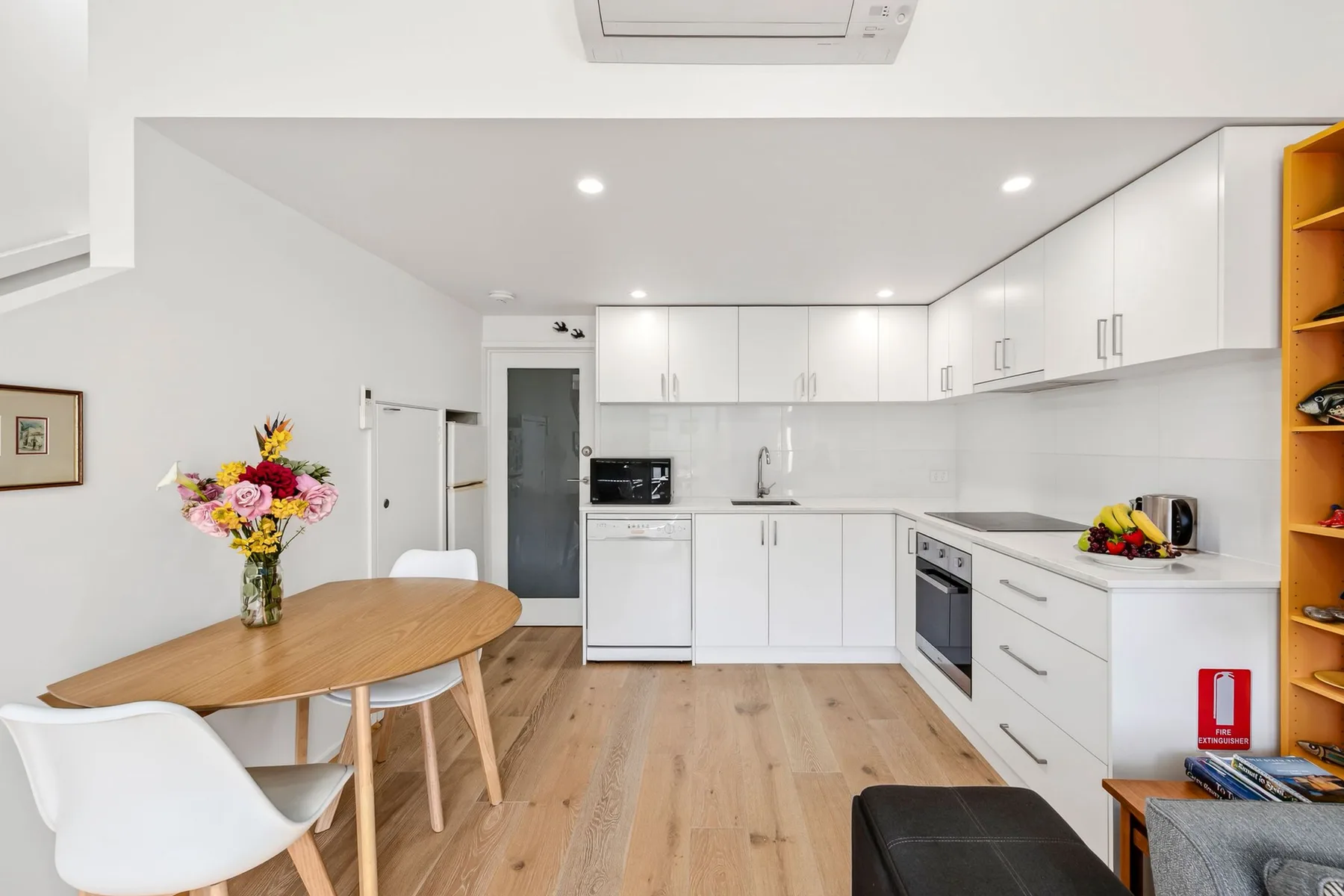 A bright kitchen and dining area with white cabinetry and a wooden table.