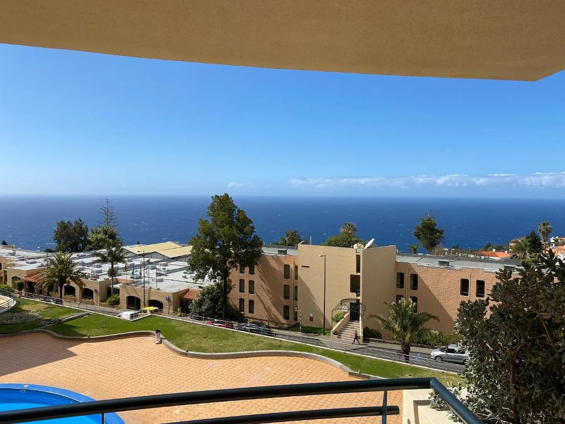 Un balcón da a edificios de apartamentos, una piscina y el océano.