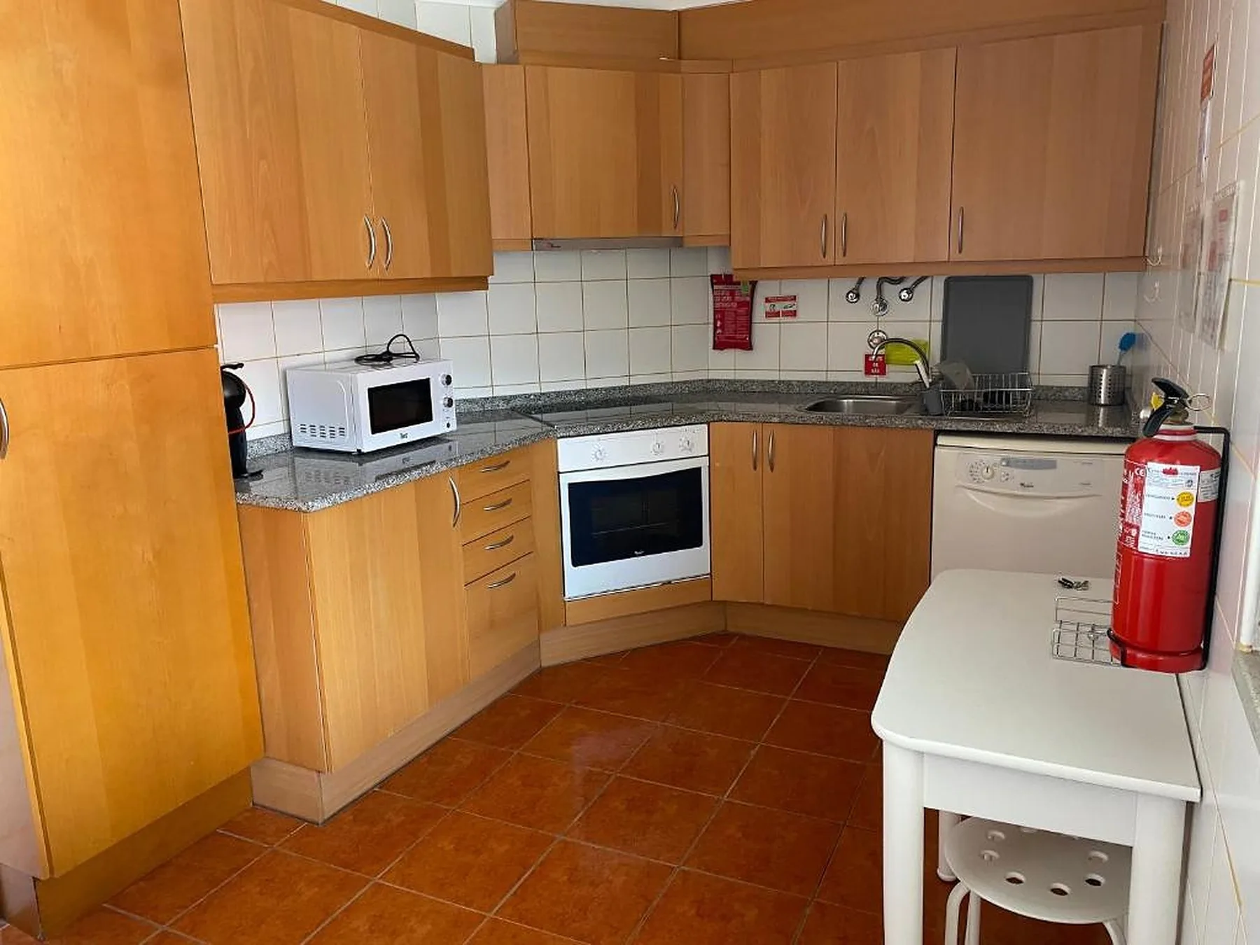 Una cocina compacta con armarios de madera, encimera y electrodomésticos.
