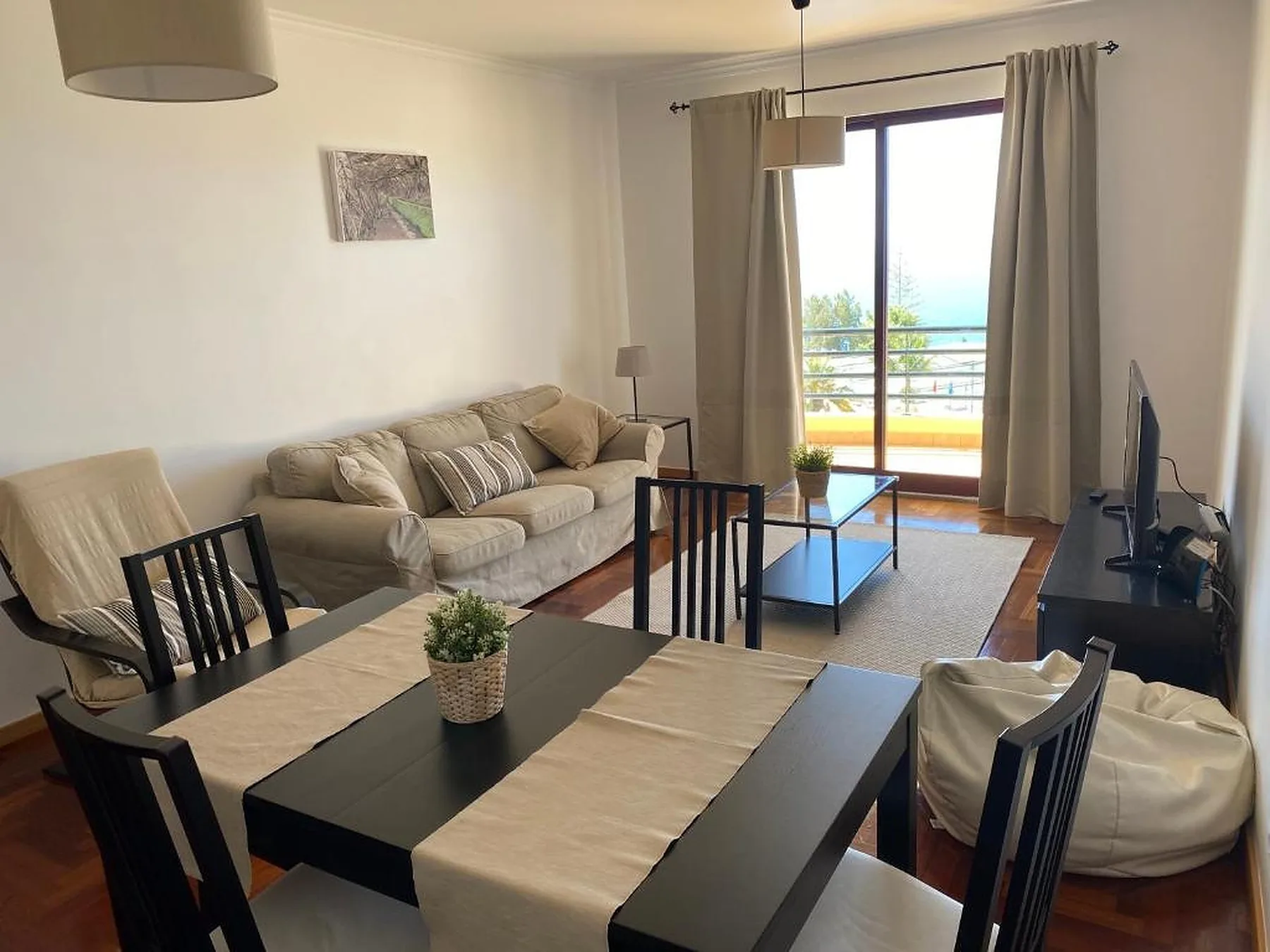 Sala de estar y comedor con sofá, mesa y puertas corredizas de vidrio.