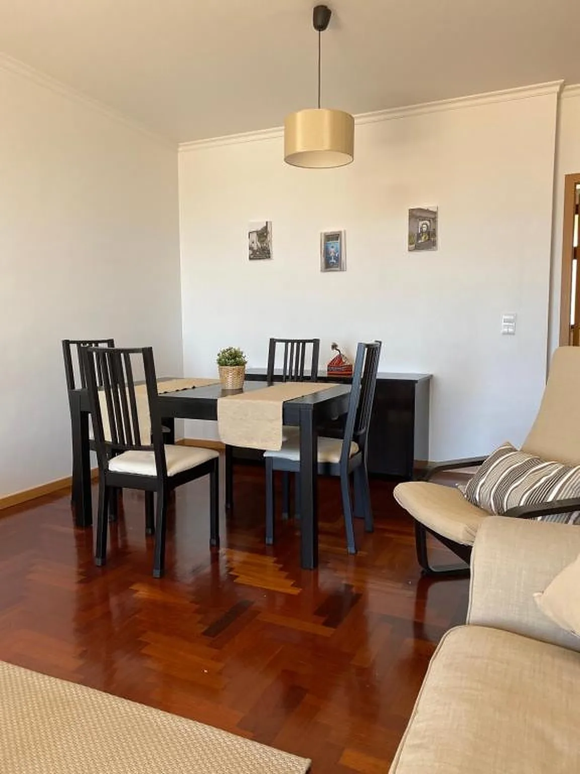 Comedor con una mesa oscura y sillas junto a un sofá de color claro.