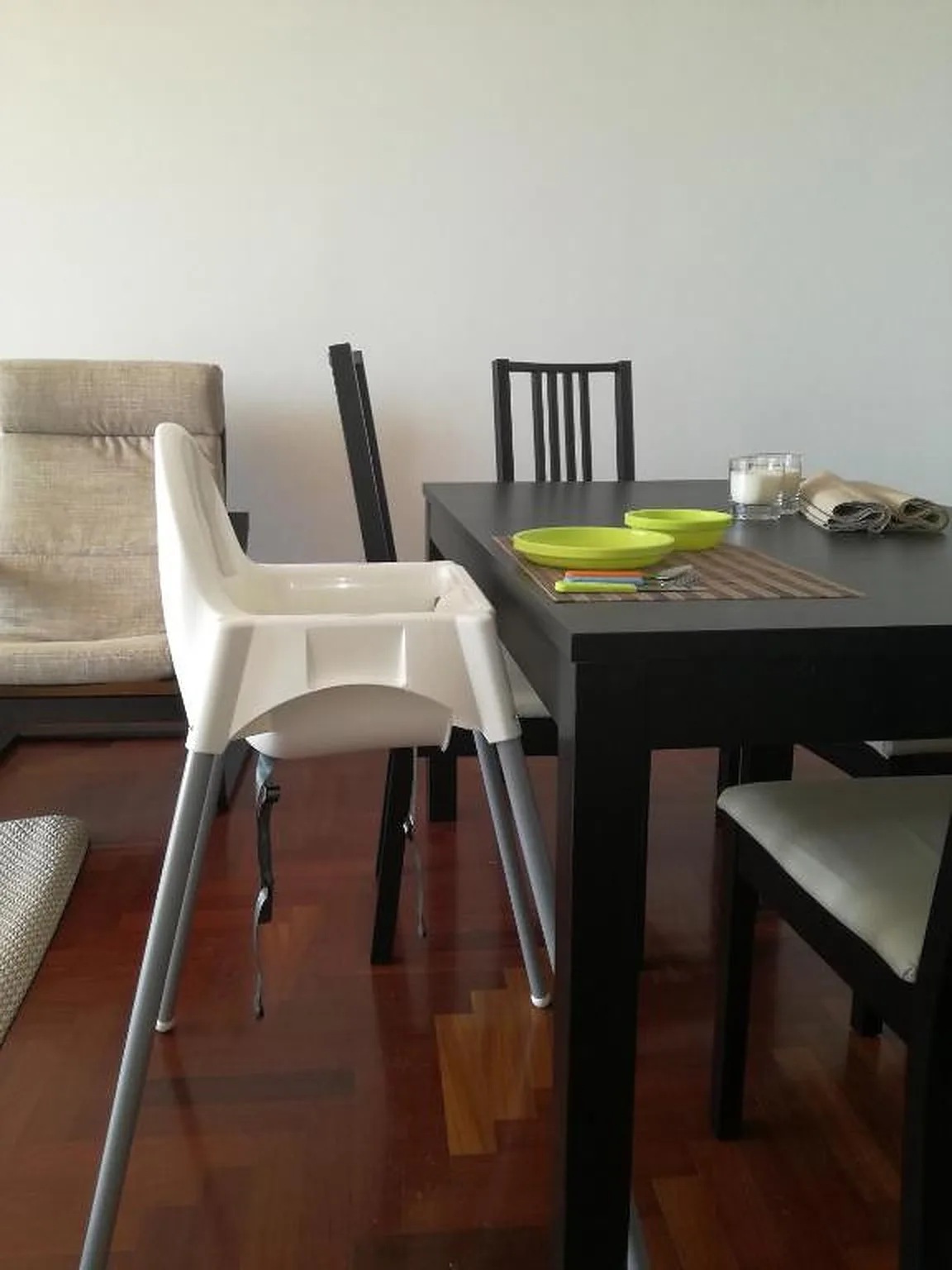 Un comedor con una mesa oscura y sillas blancas junto a un sofá.