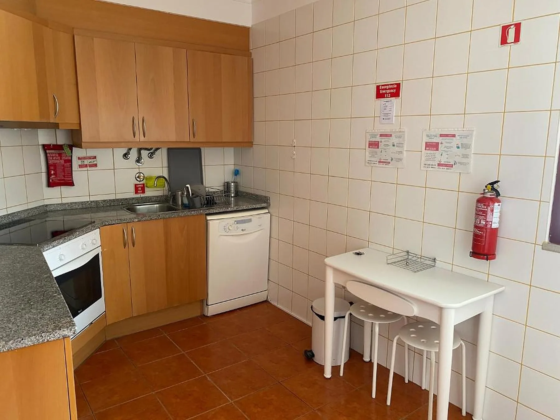 Una cocina con azulejos, armarios de madera, una encimera y una mesa pequeña.