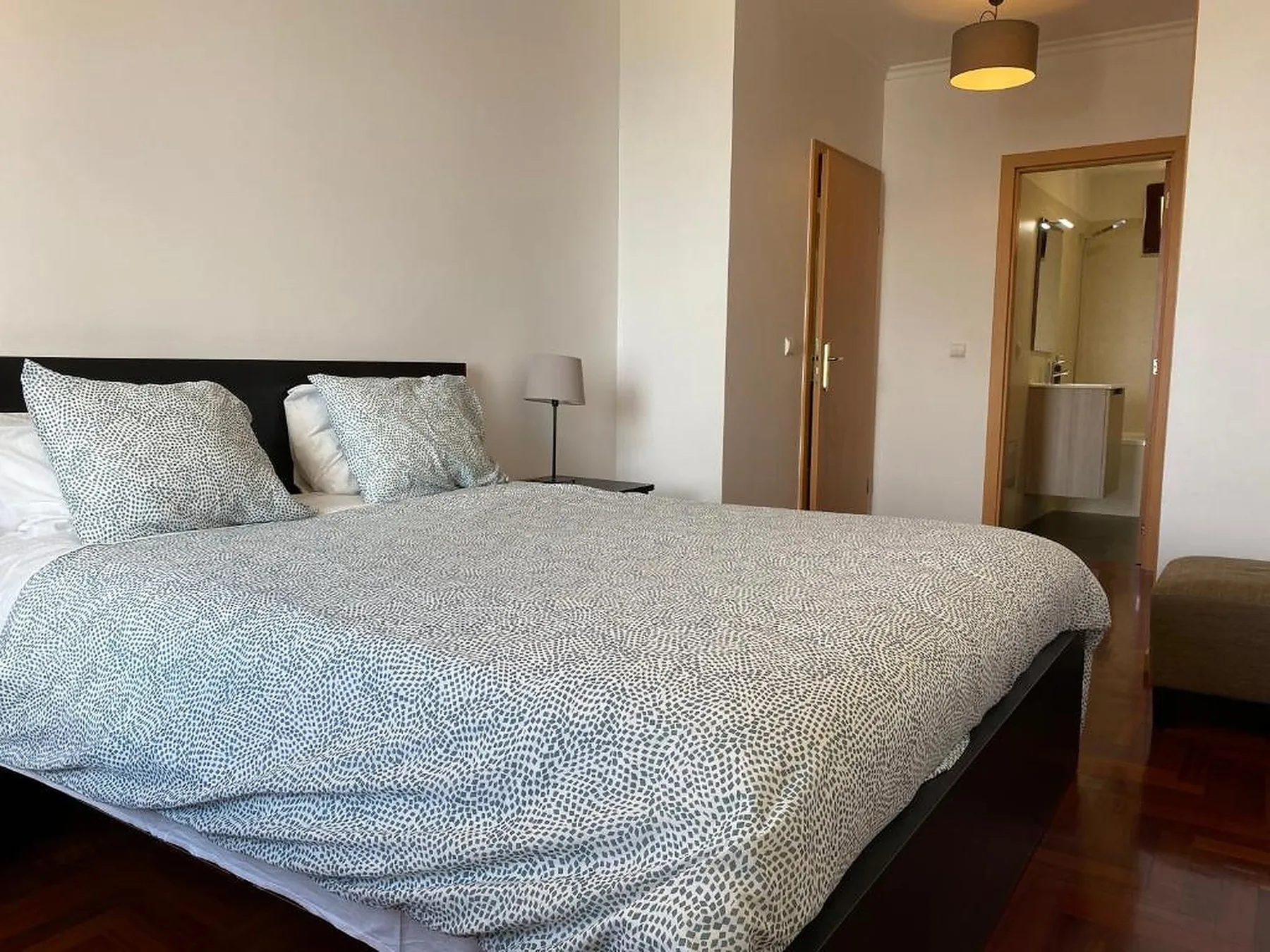 Un dormitorio con una cama bien tendida y una puerta abierta al baño.
