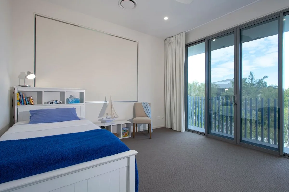 Un dormitorio con una cama y grandes puertas de vidrio que dan a un balcón.