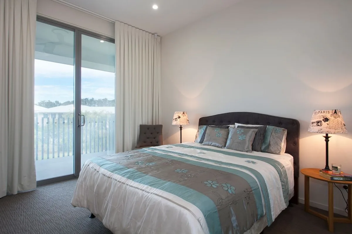 Un dormitorio con una cama junto a una puerta de vidrio que da a un balcón.