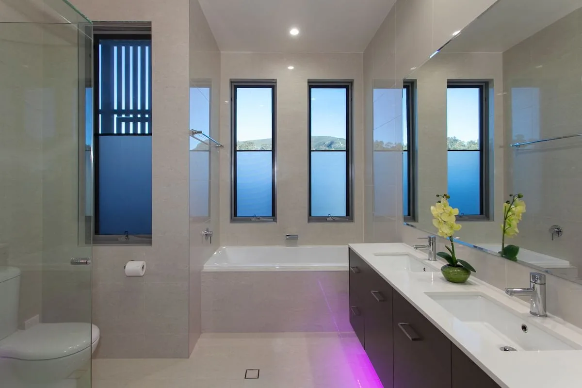 Un baño luminoso con bañera, lavabo y ventanas con vistas al agua.