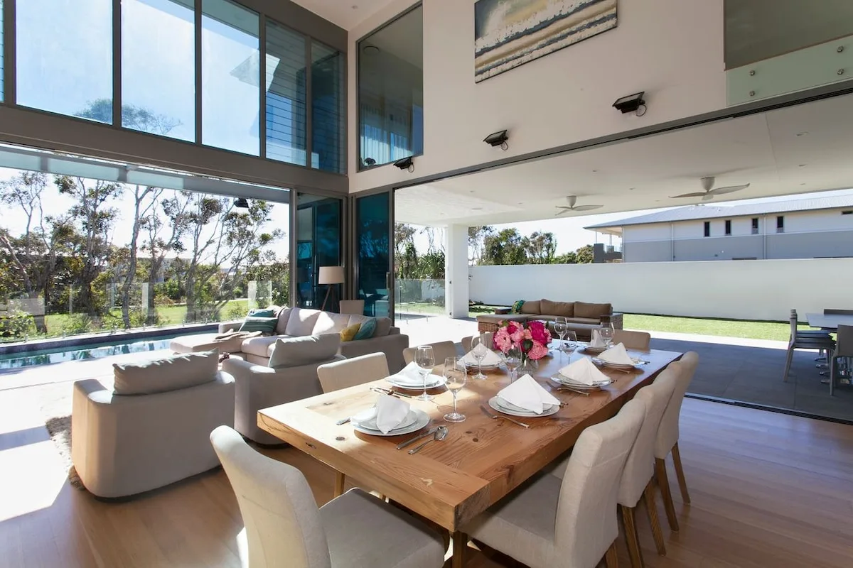 Un comedor y salón diáfanos y luminosos dan a una piscina y un jardín.