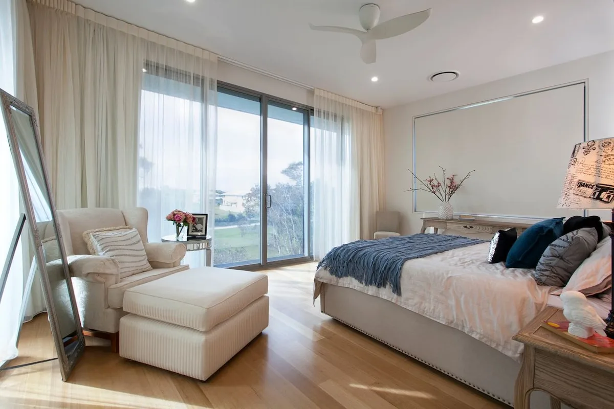 Un dormitorio luminoso con una cama grande y una zona de estar junto a ventanales.