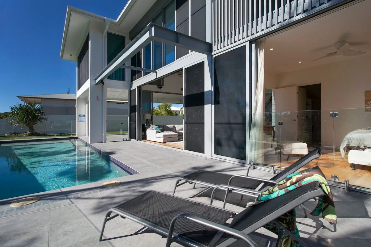 Una casa moderna da a una piscina y una zona de estar al aire libre.
