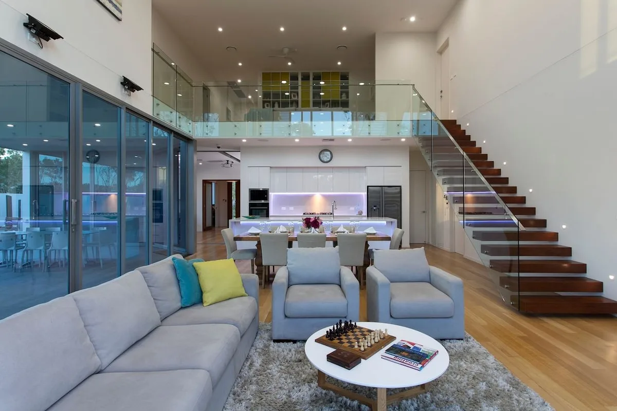 Una sala luminosa con asientos y una escalera junto a grandes puertas de vidrio.