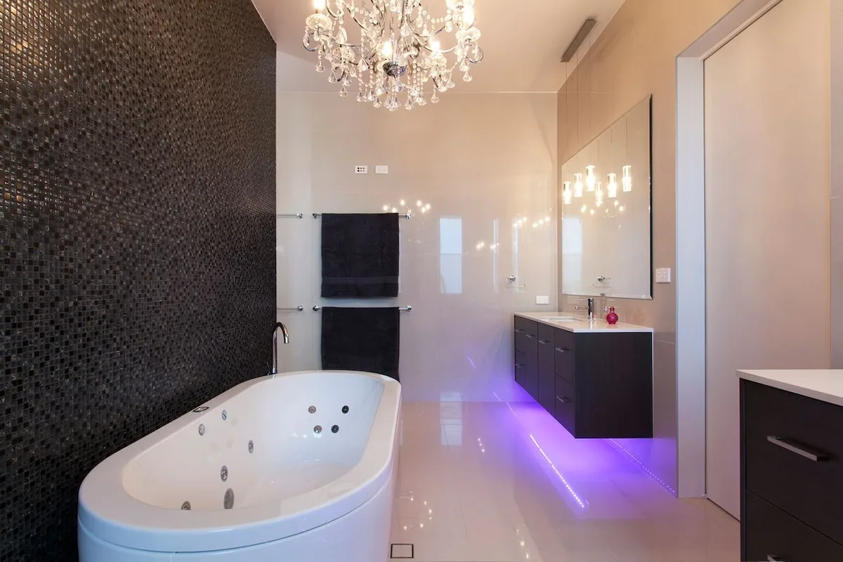 Un baño con una bañera grande, un tocador y una lámpara de araña.