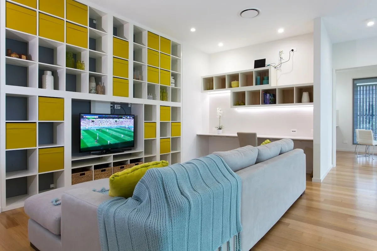 Una sala de estar luminosa con estanterías empotradas y un televisor.