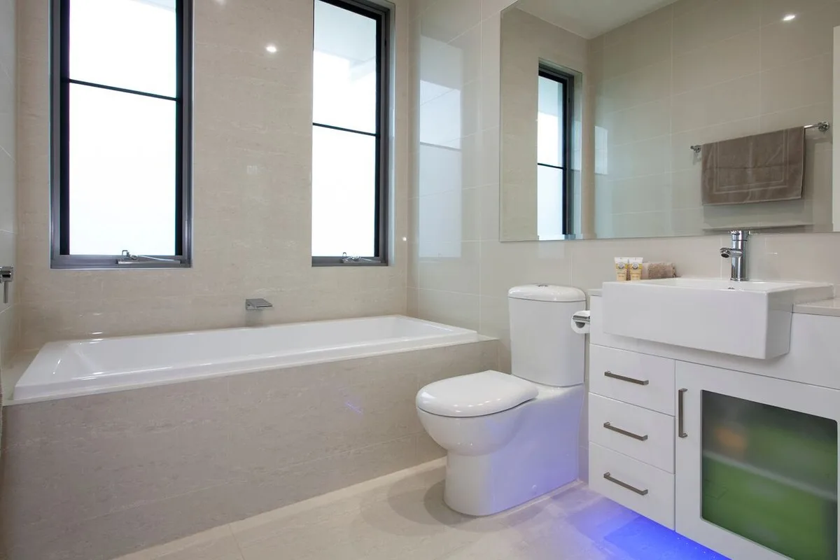 Un baño luminoso con bañera, inodoro y lavabo.