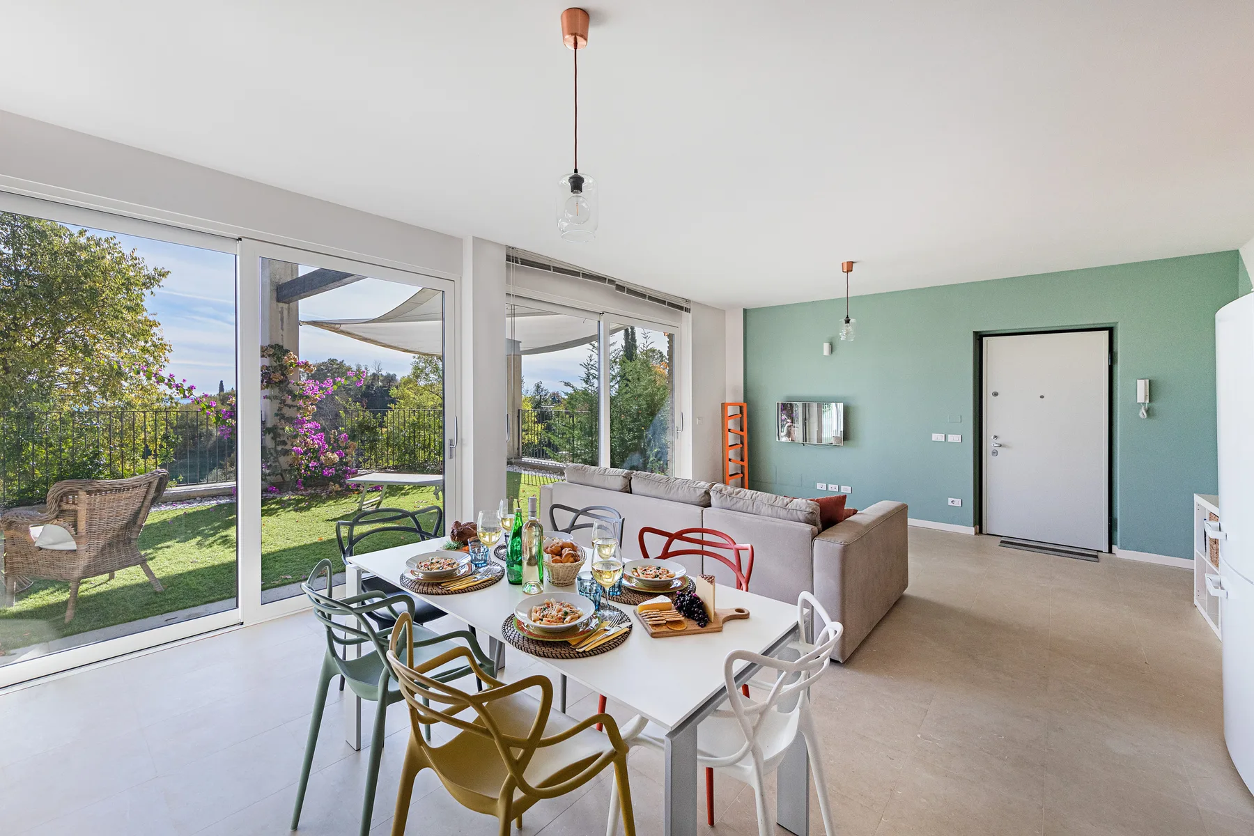 A bright dining and living area opens onto a garden through large windows.