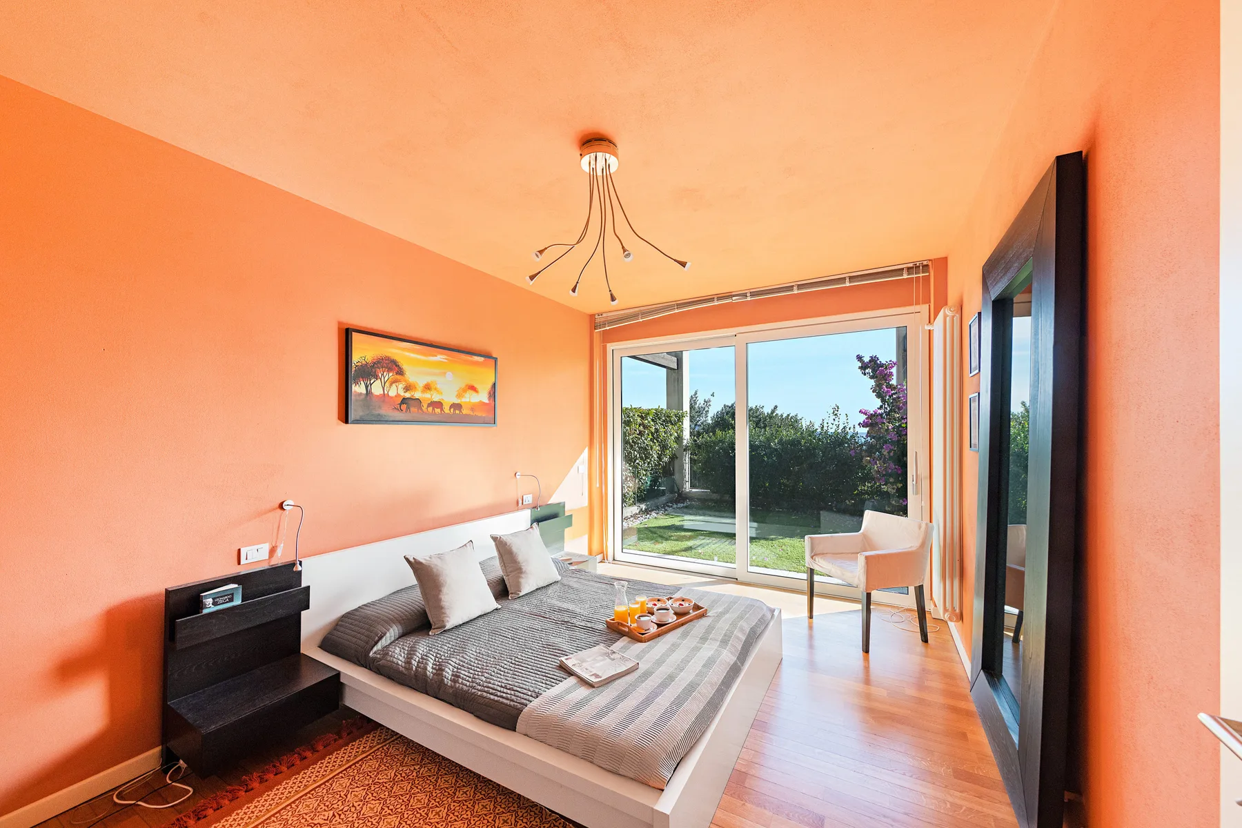 A bedroom with a bed and a glass door opening onto a garden.
