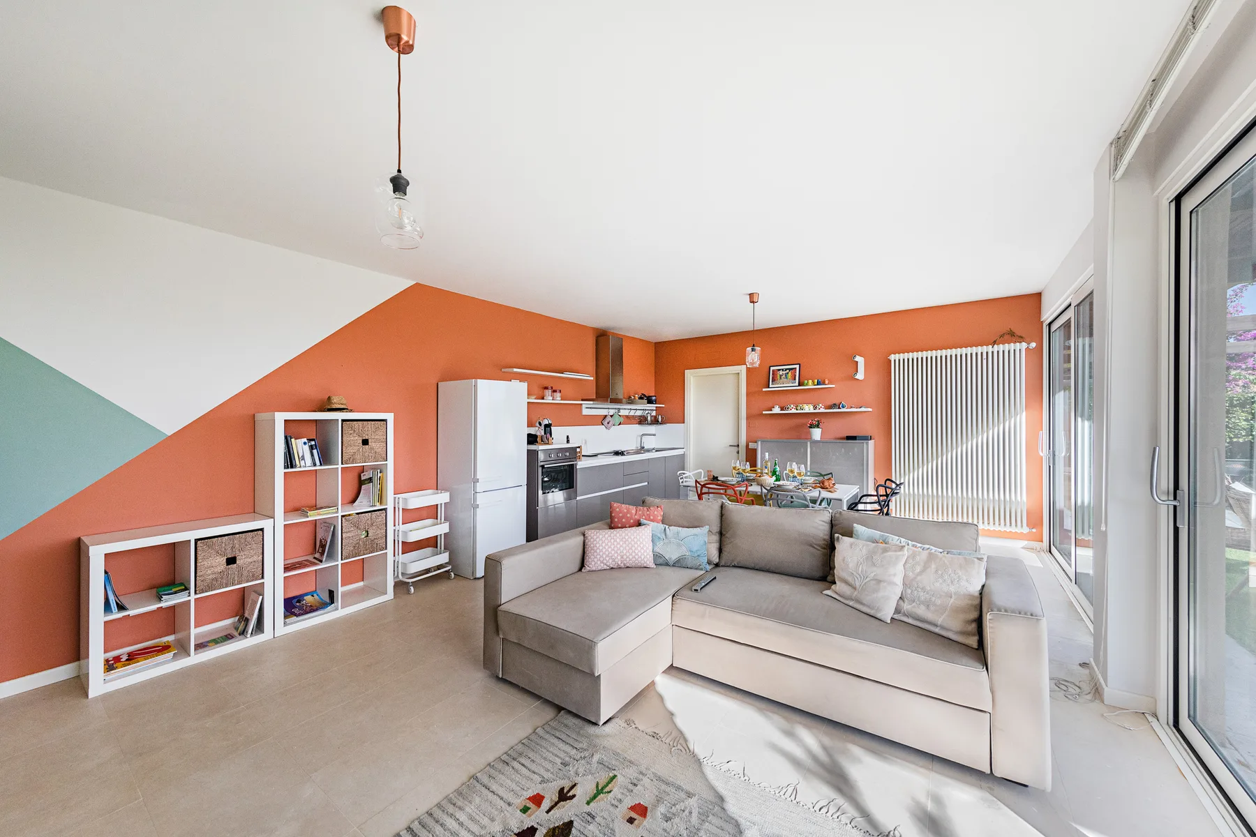 A bright living room with a sectional seating area and an open kitchen.