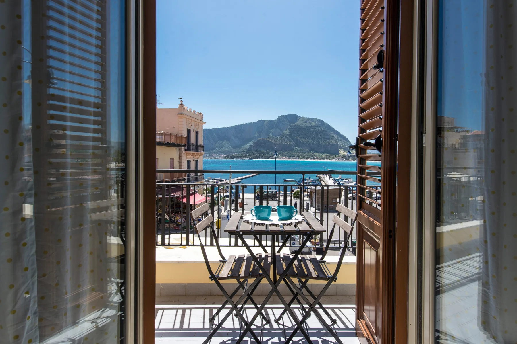 An open balcony overlooks the sea, with a small table and seating.