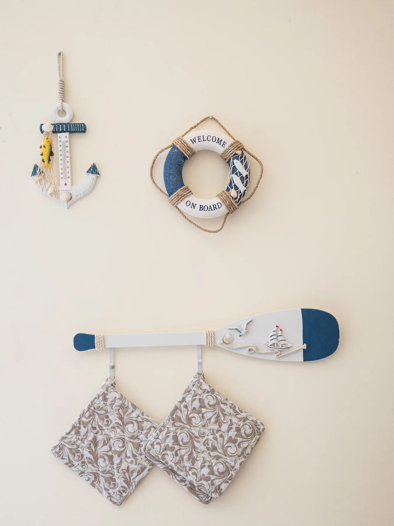 A nautical wall display features an anchor, a life ring, and patterned hanging pieces.