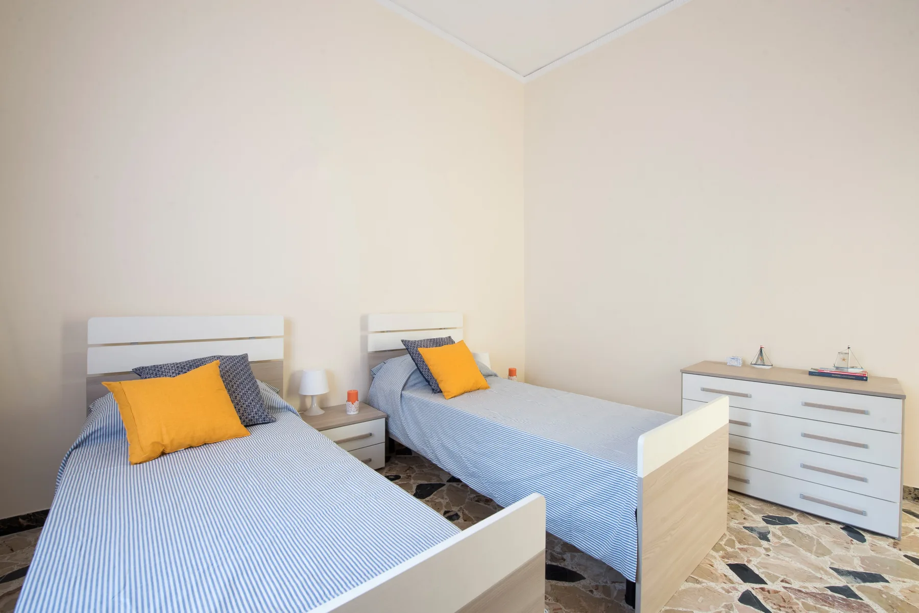 A bedroom with two single beds, each made with blue bedding.