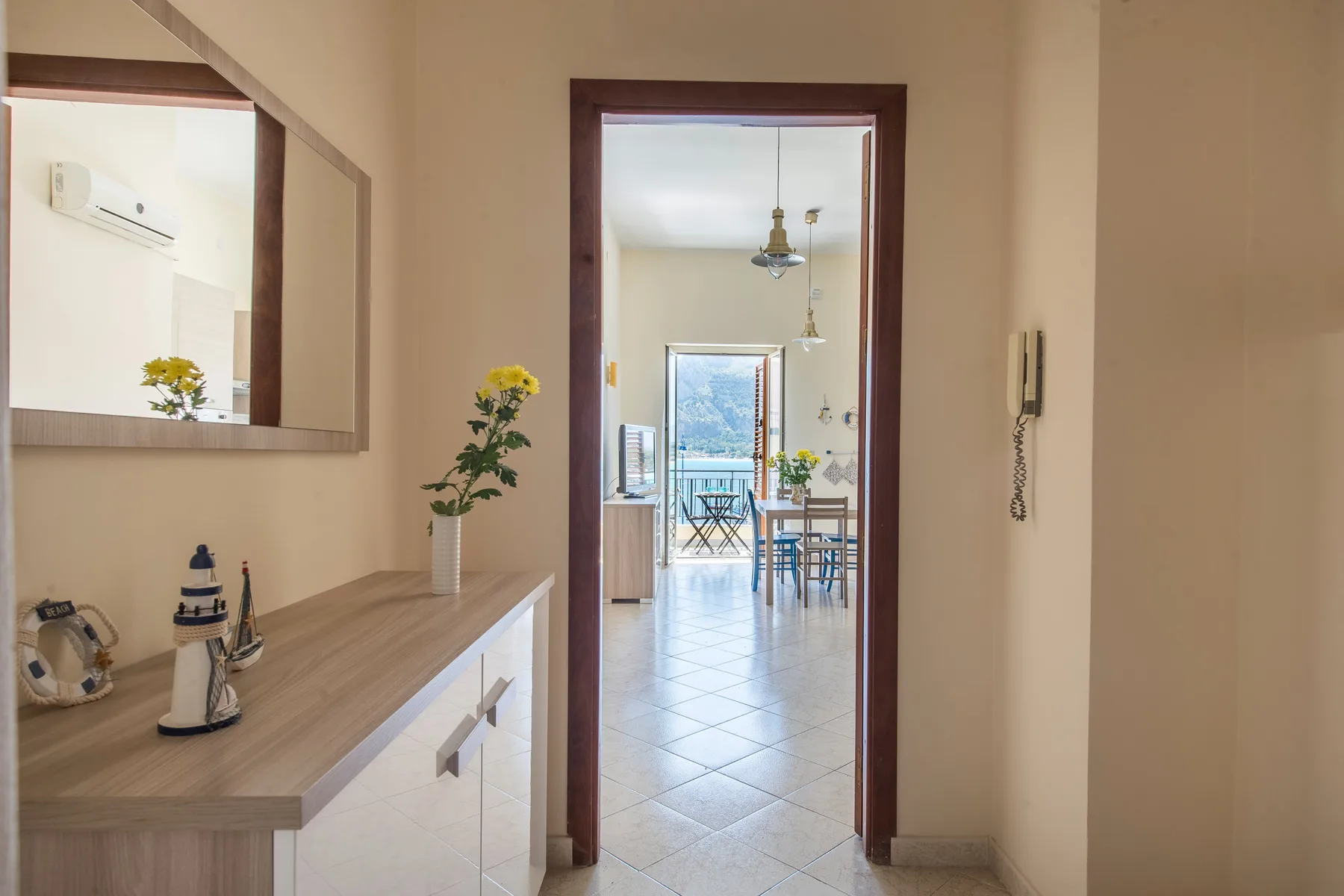 A hallway opens into a bright dining area with a table and chairs.