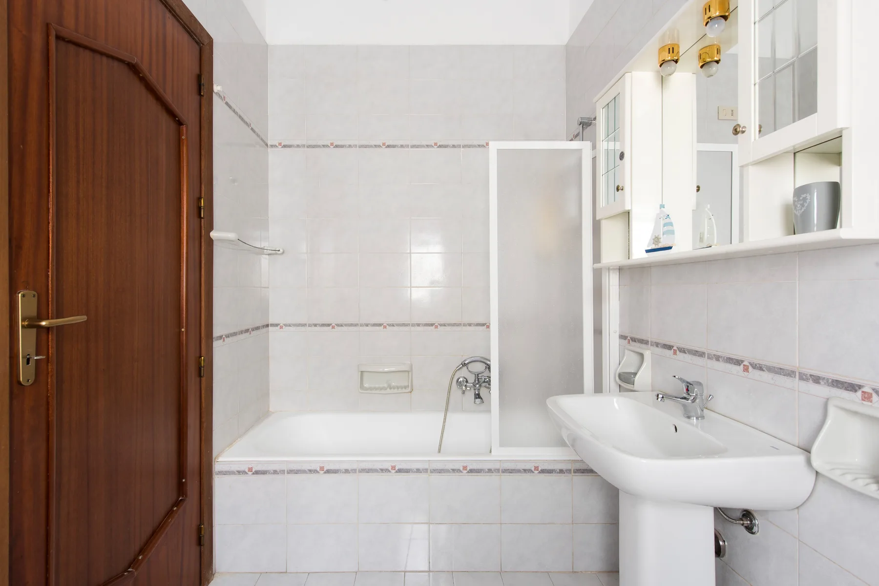 A tiled bathroom with a bathtub, shower fixtures, and a sink.