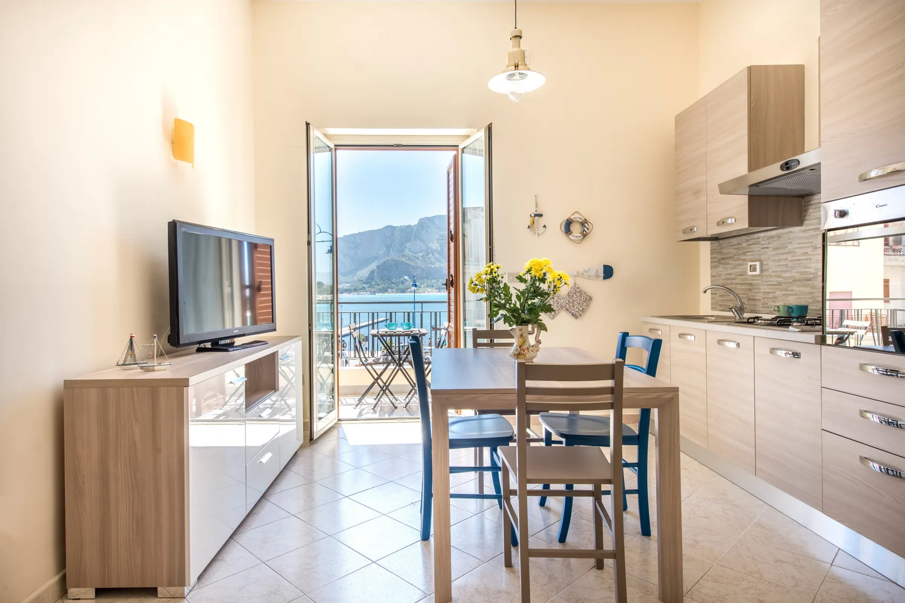 A bright dining area opens onto a balcony, with a kitchen along the wall.