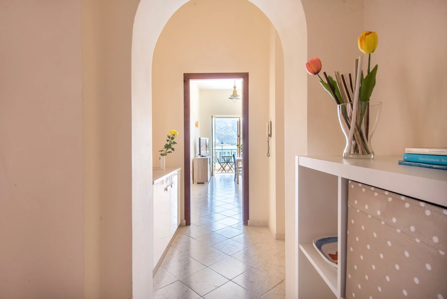 A tiled hallway extends through an arched opening toward a bright room.